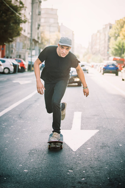 Pro skateboard rider in front of car on city street - Foto, afbeelding