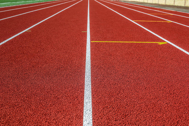 Красная беговая дорожка на спортивном поле
. - Фото, изображение