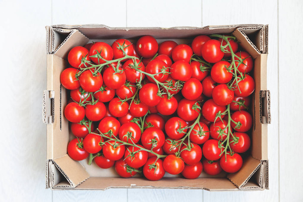 Red tomatoes on green branches lie in box - Foto, imagen