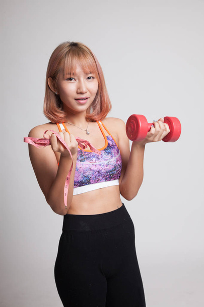 Beautiful Asian healthy girl with dumbbell and measuring tape. - Fotografie, Obrázek
