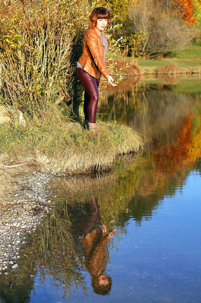 Eine junge Frau spiegelt sich im herbstlichen See - Foto, Bild