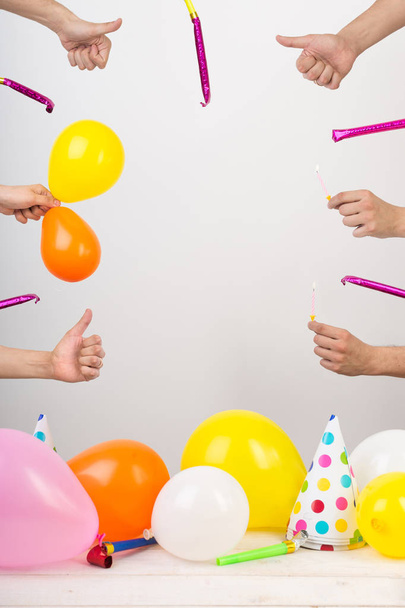 congratulation, fun, anniversary concept. pattern for card with frame of arms with thumbs up and whistles, in the lower part of the photo there are balloons and party hats. negative space for text - 写真・画像