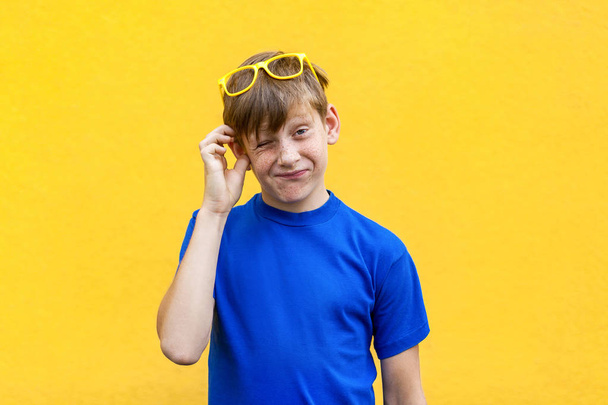 Dont sure. Confused freckled boy in yellow glasses. - Fotoğraf, Görsel