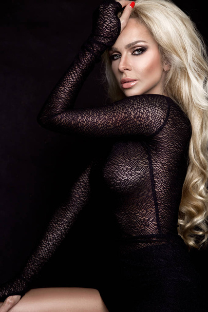 Beautiful gorgeous blonde with amazing hair in transparent dress on a black background - Valokuva, kuva