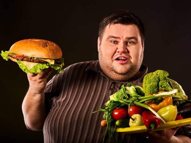 Diet fat man makes choice between healthy and unhealthy food. - 写真・画像