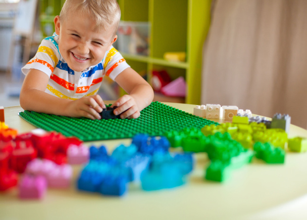 Μικρό αγόρι ξανθός παιδί που παίζει με τα μέρη, πολύχρωμο πλαστικών μπλοκ - Φωτογραφία, εικόνα