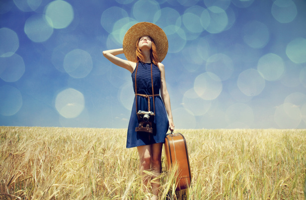 fille rousse avec valise au champ de blé de printemps
. - Photo, image