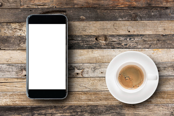 Plat lag Smartphone met leeg wit scherm en koffiekopje op houten tafel achtergrond. - Foto, afbeelding