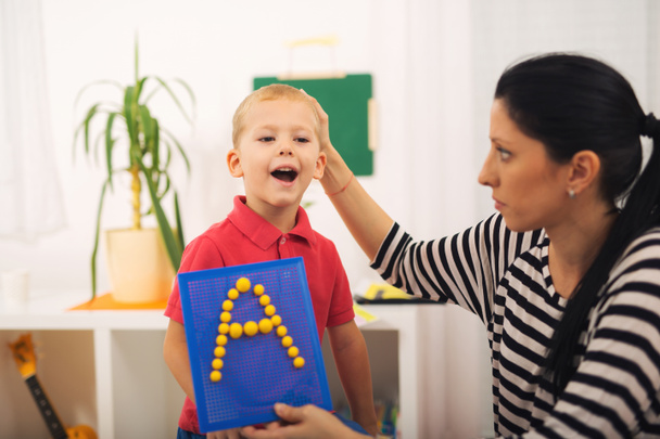 Μικρό αγόρι κατά τη διάρκεια του μαθήματος με το θεραπευτή του λόγου. Thr μάθησης - Φωτογραφία, εικόνα