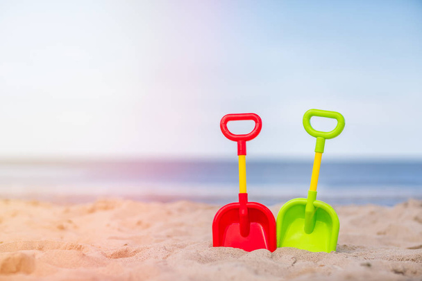 Пластиковые игрушечные лопаты на пляже
 - Фото, изображение
