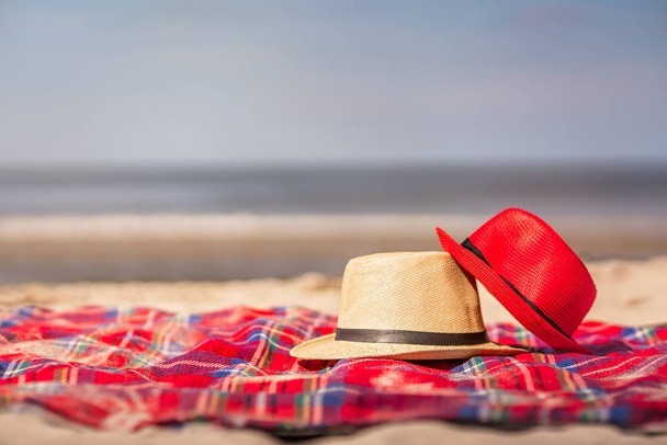 Red and white straw hats on the colorful blanket on the - Photo, Image