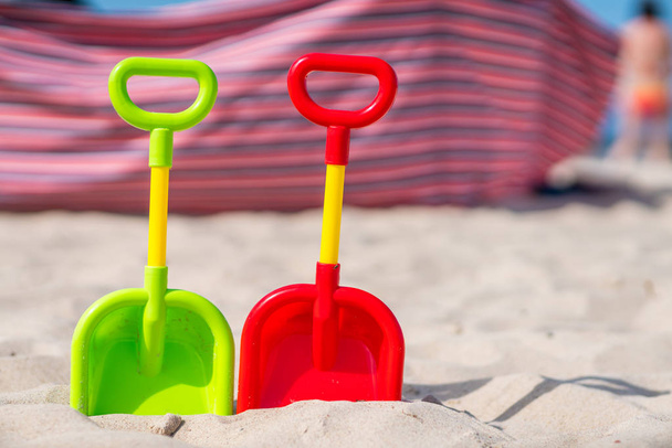 Пластиковые игрушечные лопаты на пляже
 - Фото, изображение