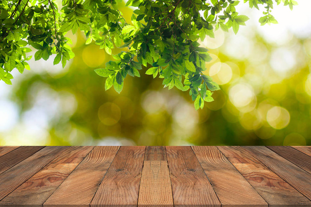 Brown wood table and green leaves hanging with nature bokeh in b - Foto, immagini