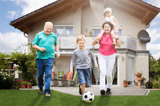 Felice nonni giocare a calcio con i loro nipoti al di fuori della loro casa
 - Foto, immagini