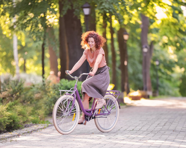 Beautiful young woman with bicycle, outdoors - Foto, afbeelding