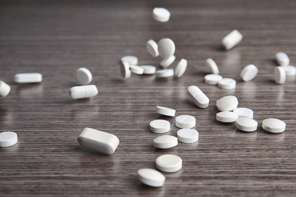 Scattering white pills on wooden table - Fotoğraf, Görsel