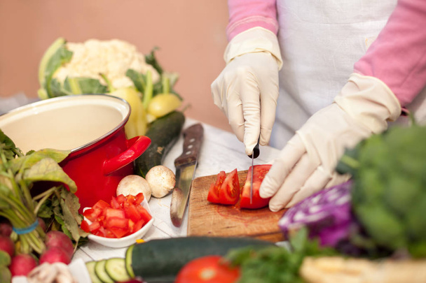 Mujer con guantes cortando tomate
 - Foto, imagen