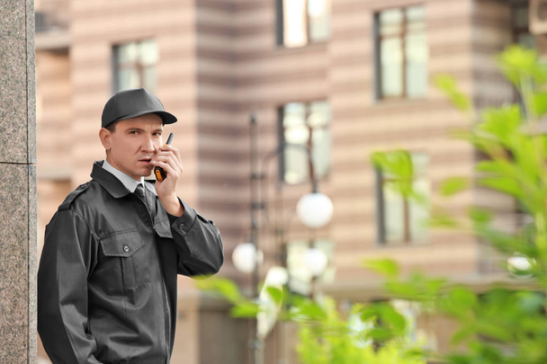 Male security guard with portable radio, outdoors - Fotoğraf, Görsel