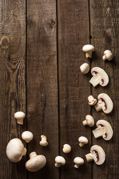 sliced champignon mushrooms on slate and wooden counter top background - Foto, afbeelding