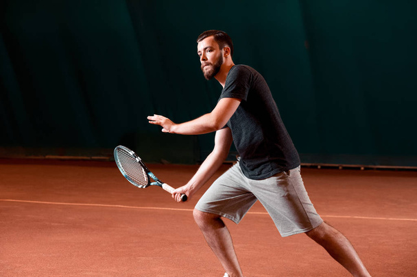 Bonito jovem em t-shirt segurando raquete de tênis na quadra de tênis
 - Foto, Imagem