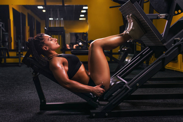 Side view of a fit young woman doing leg presses in the gym. - Foto, immagini
