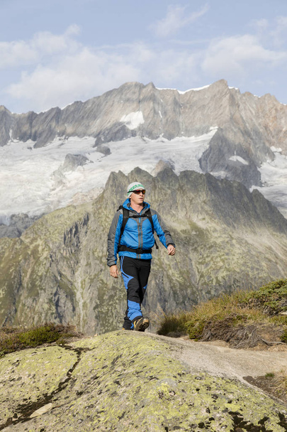 Hiker hikes through a breathtaking alpine landscape in the mountains - Photo, Image