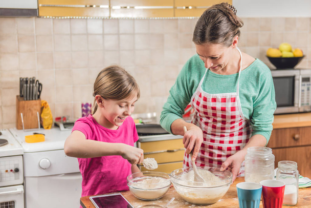Daughter and mother making dough - Foto, afbeelding