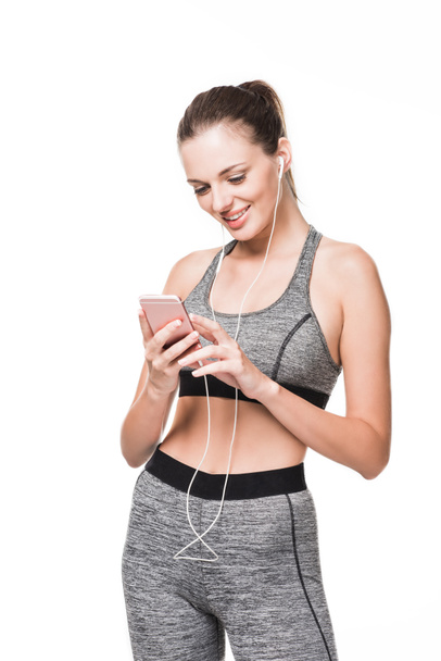 sportswoman in earphones using smartphone - Foto, afbeelding