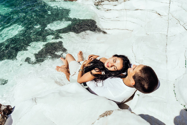 A young couple of lovers lies in beautiful clear water near white rocks on the Maldives - Φωτογραφία, εικόνα