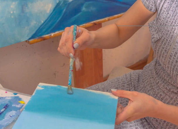 painter girl with brush, paints a small canvas. - Fotó, kép