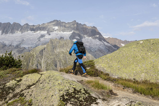 Hiker hikes through a breathtaking alpine landscape in the mountain - Photo, Image