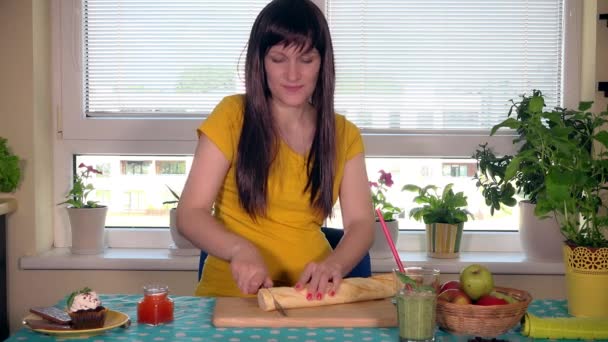 Kobieta w ciąży, krojenie bagietka chleb z nożem na deska do krojenia - Materiał filmowy, wideo