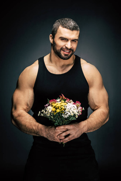 sportive man with bouquet of flowers - Foto, afbeelding