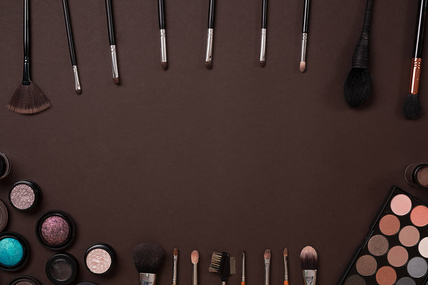 Make up essentials. Set of professional make up brushes, creams and shadows in jars on dark background. - Photo, image