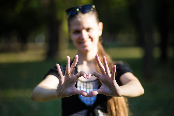 Jonge vrouw maakt handen in de vorm van liefde hart - Foto, afbeelding