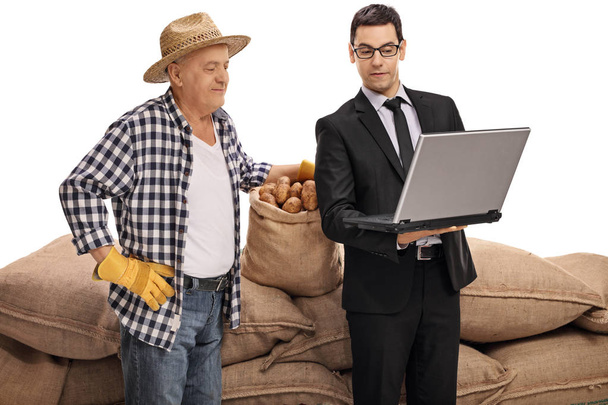 businessman showing something on a laptop to a farmer - Foto, Imagen