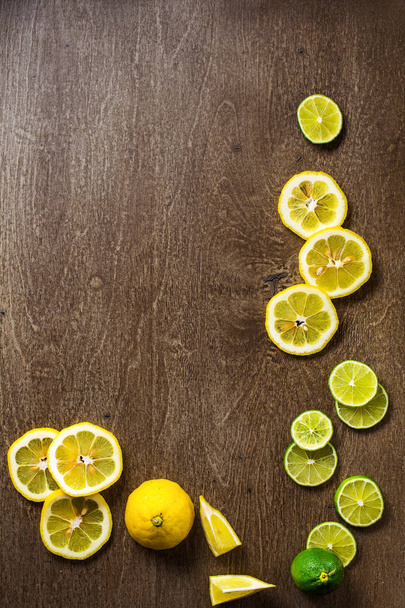 sliced lemon, lime on  slate and wooden counter top background - Foto, imagen