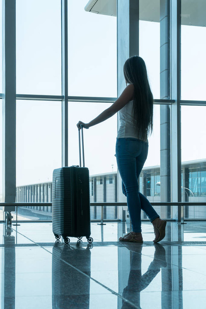 Дівчина мандрівник з валізою і документами, щоб підготуватися до наступної поїздки. Дівчина стоїть в аеропорту. Концепція подорожей
 - Фото, зображення