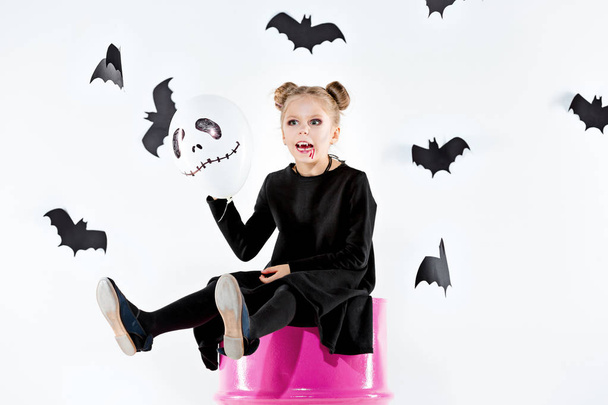 Little girl witch in black dress over magical accessories. Halloween, the studio evening. - Φωτογραφία, εικόνα