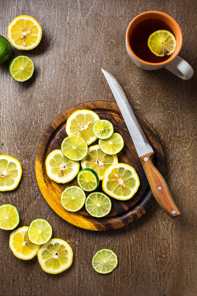 gesneden op citroen, limoen leisteen en houten counter top achtergrond - Foto, afbeelding