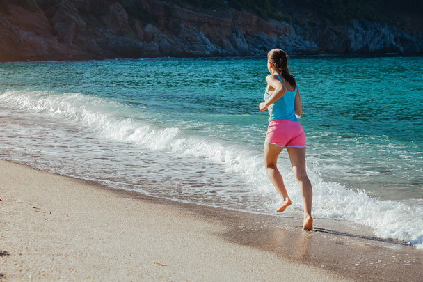 Jeune femme courant sur la plage - Photo, image