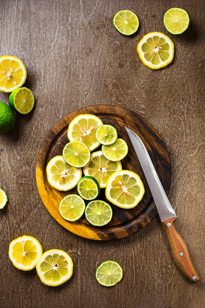 sliced on lemon, lime slate and wooden counter top background - Zdjęcie, obraz