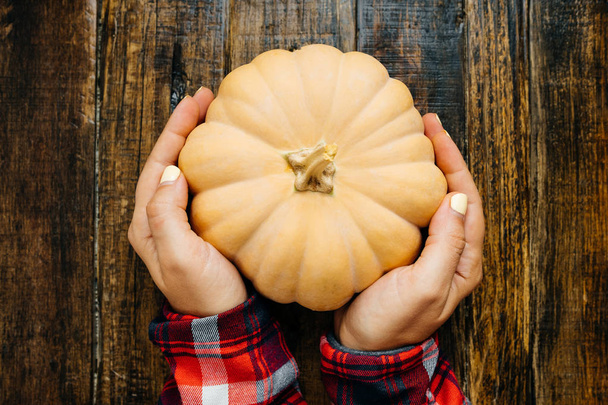 Woman hands with Pumpkin and dry leaves on a wooden background.  - 写真・画像