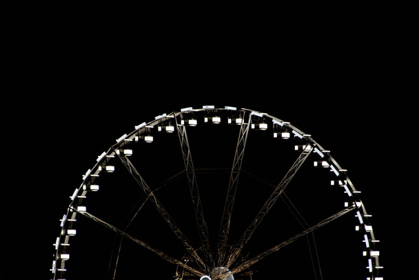 A ferris wheel cropped in half at night time - Фото, зображення