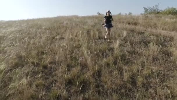 A girl with a backpack on her shoulders runs away from a steep slope. - Felvétel, videó