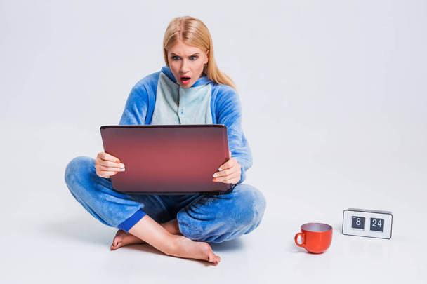 ノート パソコンでパジャマ姿で床に座っていた若い女性. - 写真・画像