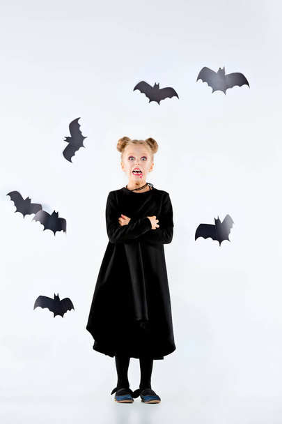 Маленька дівчинка відьма в чорній сукні над чарівними аксесуарами. Хеллоуїн, студійний вечір
. - Фото, зображення
