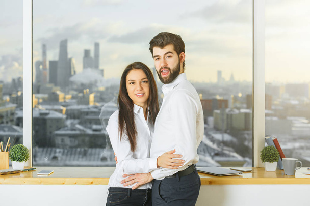 Side view of hugging couple in modern office interior with blurry city view. Romance concept  - Foto, immagini