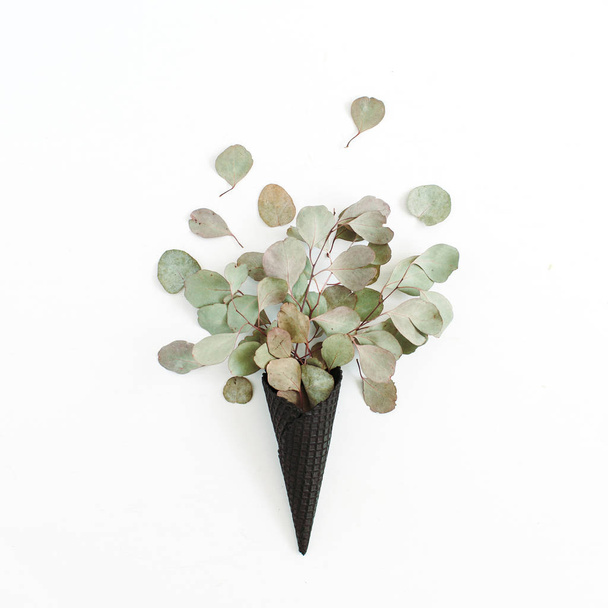 Cone de waffle de sorvete preto com folhas de eucalipto secas
 - Foto, Imagem