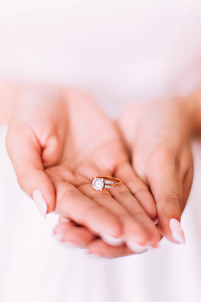 Golden wedding ring in hands of the bride. - Foto, afbeelding